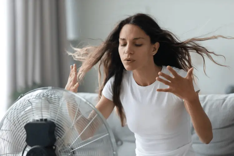 Millennial girl suffer from hot weather use floor fan